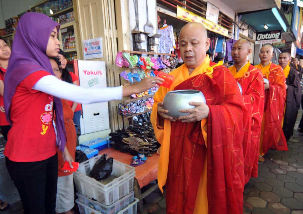 Une employée d’un magasin musulman donne l’aumône à des moines bouddhistes.