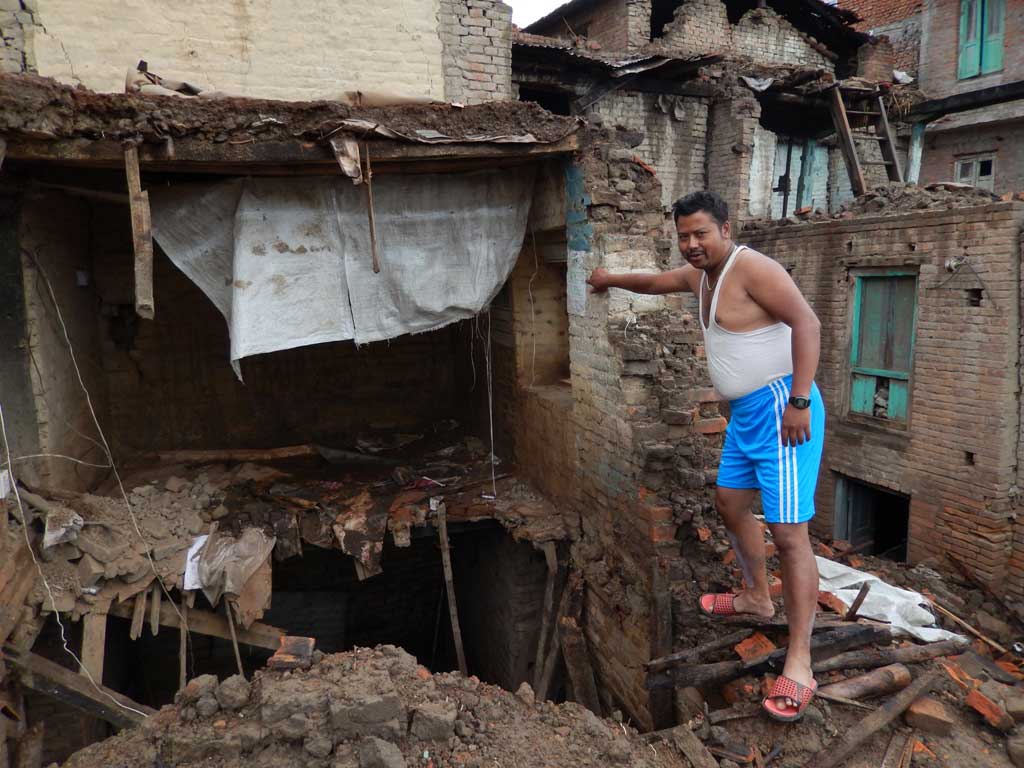 Ajay Maharjan montrant ce qui reste de sa maison à Jyako Tole, dans la ville de Harisiddhi, deux mois après le séisme du 25 avril. (Crédit : Stéphane Huët)