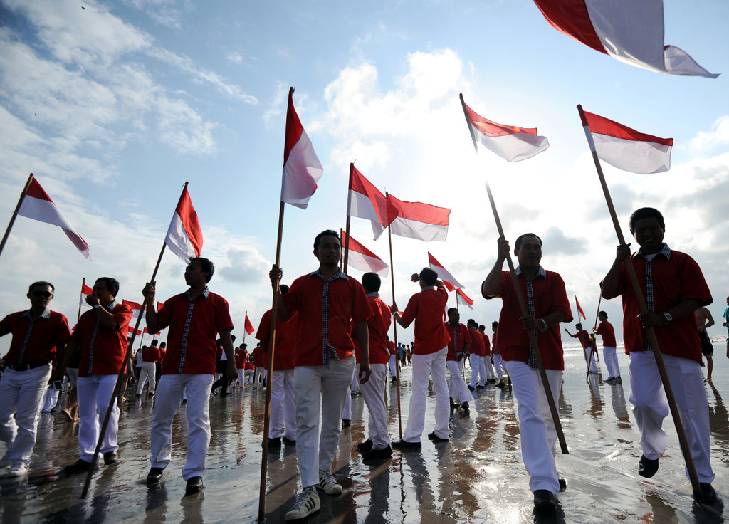 Des Balinais agitent des drapeaux indonésien lors de la célébration de l'anniversaire de l’indépendance sur une plage de Kuta