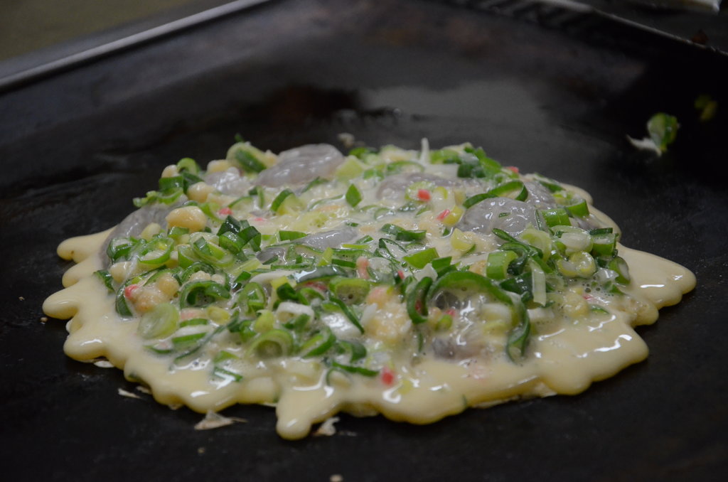 Voici la dernière des préparations d’Osaka : l’okonomiyaki. Cette préparation se présente sur un teppan (plaque chauffante). Et petit plus d’Osaka, ici on mélange tout, du poireau et des crevettes