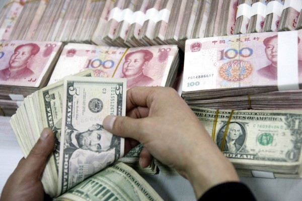Un employé de banque chinois compte des billets en dollars et en yuans dans une banque de la ville de Huabei, dans la province de l’Anhui, à l’est de la Chine, le 13 janvier 2011. (Crédit : Xie zhengyi / Imaginechina / via AFP)