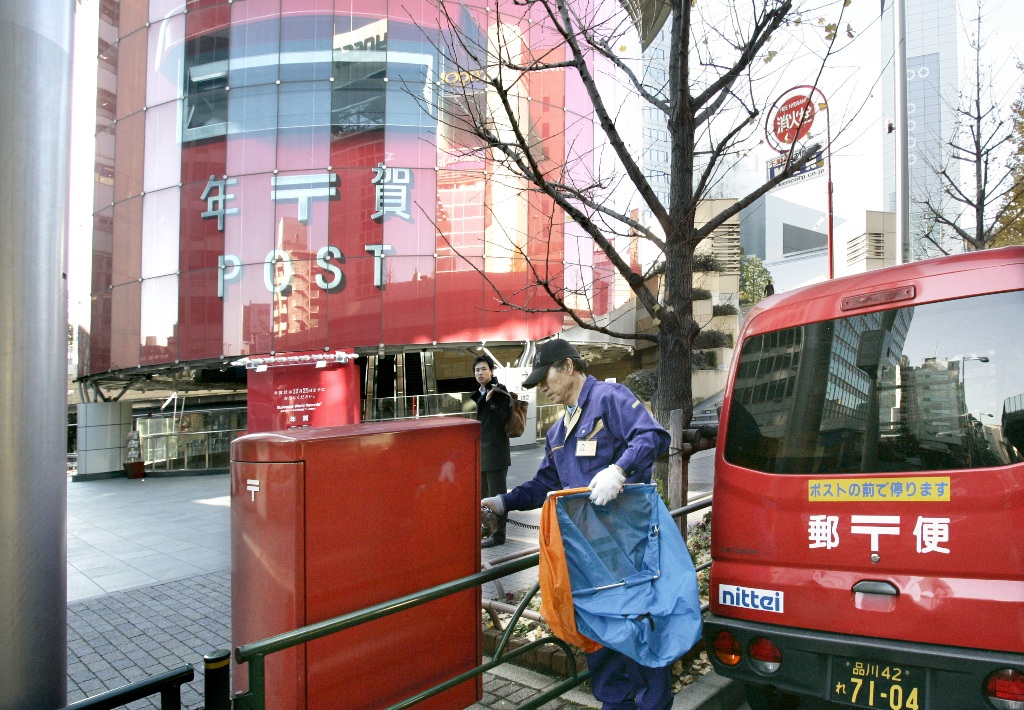 Un facteur collecte le courrier près d’une station de métro à l’apparence d’une gigantesque boîte aux lettres, à Tokyo le 15 décembre 2008. (Crédit : AFP PHOTO / Yoshikazu TSUNO)