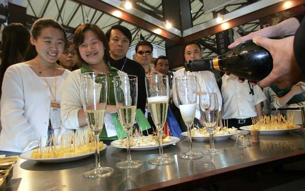 Des visiteurs admirent le service lors d’une foire internationale de la gastronomie à Shanghai en mai 2005. (Crédit : LIU JIN / AFP)