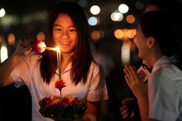 Une jeune fille thaïlandaise allume de l'encens lors du "Festival de la pleine lune et des lanternes volantes", à Chiangmai le 22 novembre 2015.