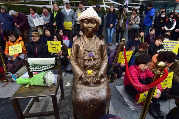 Le 11 novembre 2015, des manifestants sont assis à côté de la statue symbolisant les “Femmes de réconfort” coréennes.