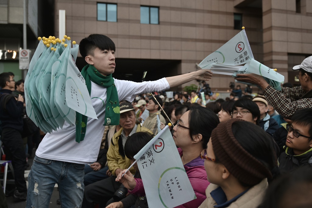 Un jeune militant du parti démocrate-progressiste, vainqueur historique de la présidentielle et des législatives à Taïwan, distribue des drapeaux aux fidèles du parti à la clôture des bureaux de vote le 16 janvier 2016 à Taipei.