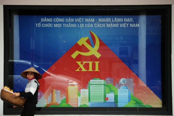 A Hanoi, un vendeur ambulant passe devant une affiche annonçant la réunion prochaine du XIIème Congrès du parti communiste vietnamien