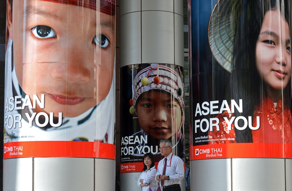 Des employés de bureau thaïlandais passent devant une publicité pour la Communauté économique de l'ASEAN à Bangkok le 14 janvier 2013.