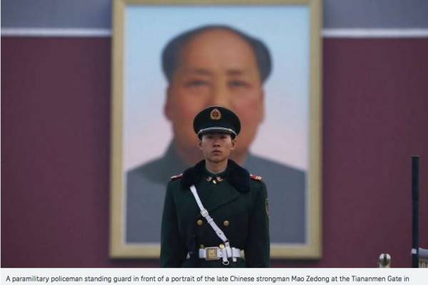 Un soldat chinois se tient debout devant le portrait de Mao Zedong.