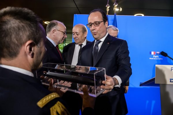 Le président François Hollande tient un modèle réduit de sous-marin du constructeur français DCNS lors d'une visite dans les locaux de l'entreprise de défense à Paris le 26 avril 2016.
