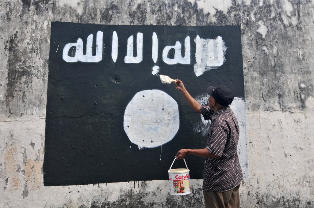 Un employé du gouvernement détruit la peinture d'un drapeau de l'Etat islamique dans la ville de Surakarta (Solo) dans la province de Java Central pour décourager la promotion du groupe djihadiste en Indonésie.