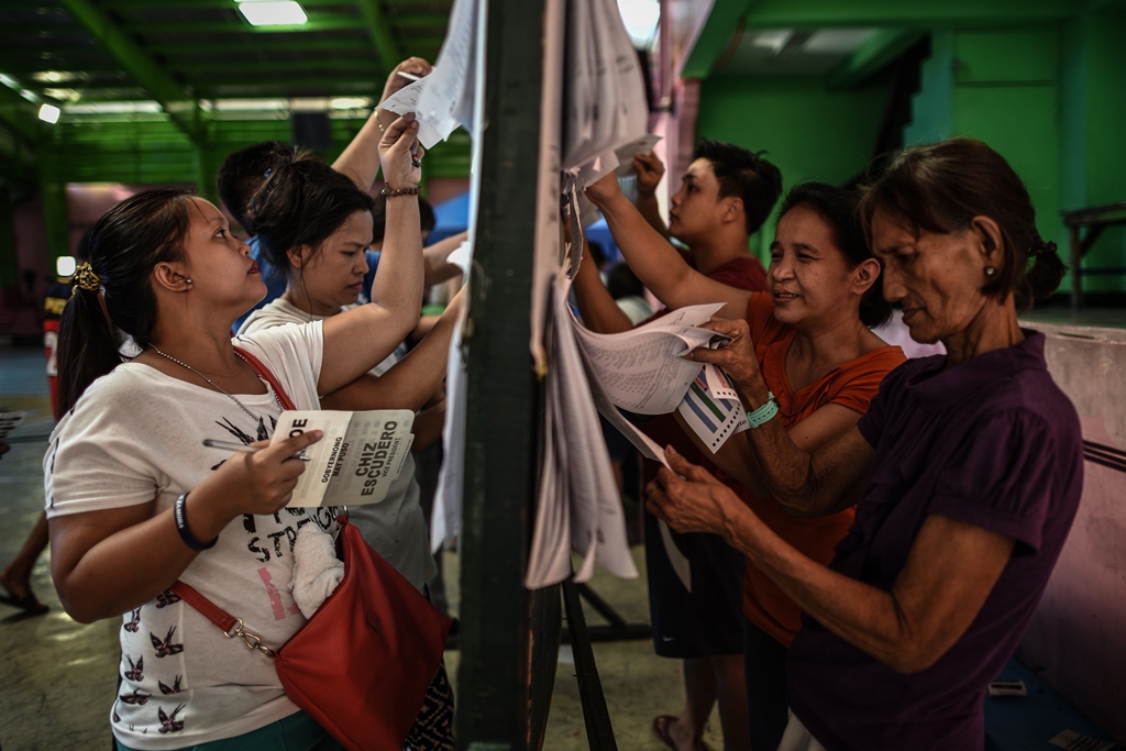 Des électeurs philippins cherchent leur nom sur les listes d'émargement avant d'aller voter aux élections présidentielles, parlementaires et locales, à Manille le 9 mai 2016.