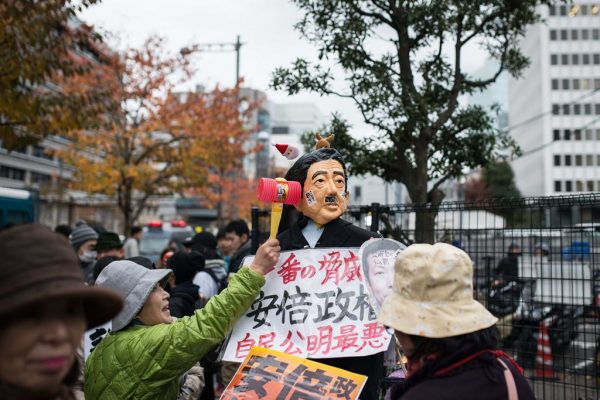 Une femme donnant un coup de marteau à la marionnette représentant le Premier ministre Shinzo Abe, en signe de protestation contre sa politique.
