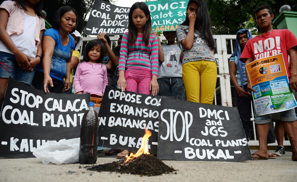 Des résidents de Calaca regardent brûler un tas de terre ramassé à côté de la centrale à charbon dans leur ville, lors d'une manifestation devant le bureau du ministère de l'Environnement à Manille aux Philippines le 17 mars 2016.