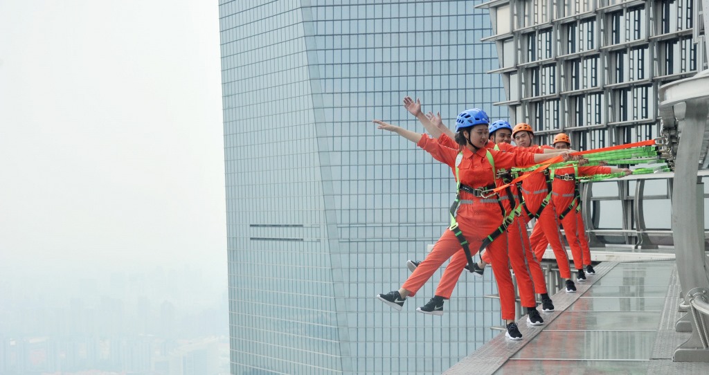 Des visiteurs équipés de harnais et de protections à l'extérieur du 88ème étage de la Tour Jinmao dans le quartier de la finance de Lujiazui, dans le district de Pudong à Shanghai, le 28 juillet 2016.