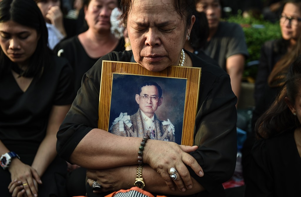 Une Thaïlandaise se recueille après le passage du corbillard transportant le corps du roi Bhumibol Adulyadej devant le Grand Palais à Bangkok, le 14 octobre 2016.