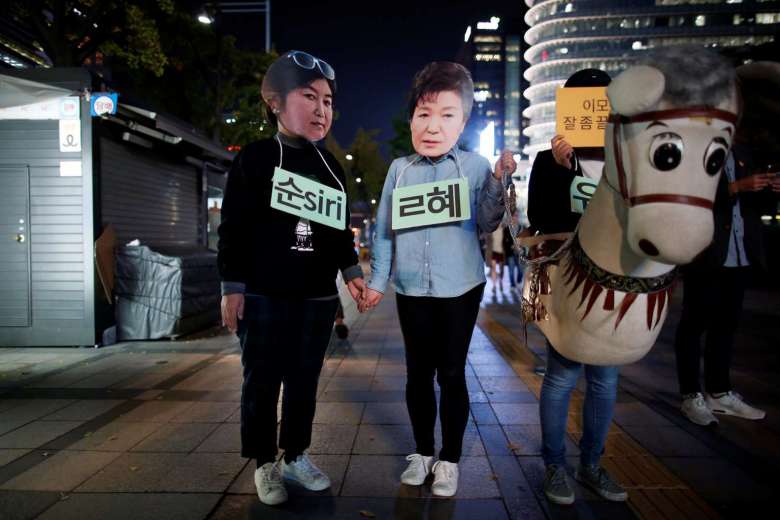 Des manifestants sud-coréens portant le masque de la présidente Park Geun-hye et de sa confidente Choi Soon-sil lors d'un rassemblement contre Park, à Séoul le 27 octobre 2016. Copie d'écran du Korea Times, le 3 novembre 2016.
