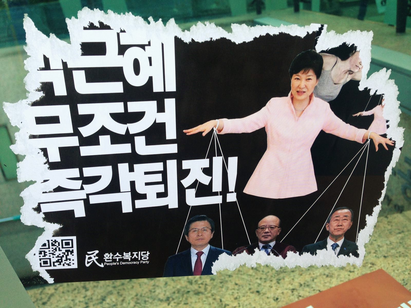 Sur cette affiche placardée à Séoul, appelant à la destitution de la la présidente sud-coréenne présentée comme une marionnette, on peut lire : "Park Geun-hye, démission immédiate et sans condition". Ce poster, copie parodique d'affiches de partis officiels, jusque dans le nom du parti inventé de toutes pièces "Parti de la démocratie du peuple", est caractéristique du vent de liberté qui anime la jeunesse. Cette photo prise à Séoul date du 11 décembre 2016, deux jours après que l'Assemblée nationale a voté la destitution de la présidente le vendredi 9 décembre.