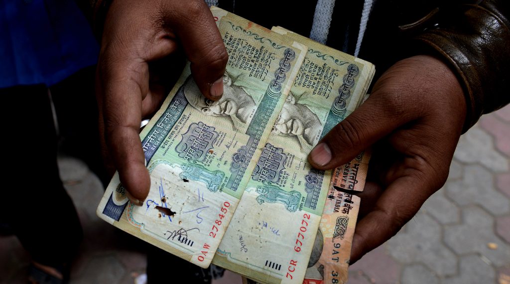 Un Indien posté devant la banque centrale à New Delhi le 30 décembre 2016, montre de vieux billets de banque frappés d'invalidité par l'opération de démonétisaiton lancée par le Premier ministre Narendra Modi le 8 novembre 2016. (Crédits : Money SHARMA / AFP)