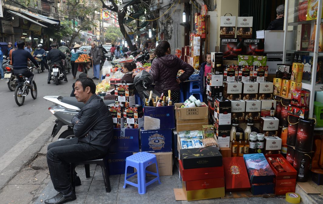 Un homme assis devant une boutique du centre-ville de Hanoi proposant du vin, des chocolats et autres boissons au moment des célébrations du Tet, le 23 janvier 2017.