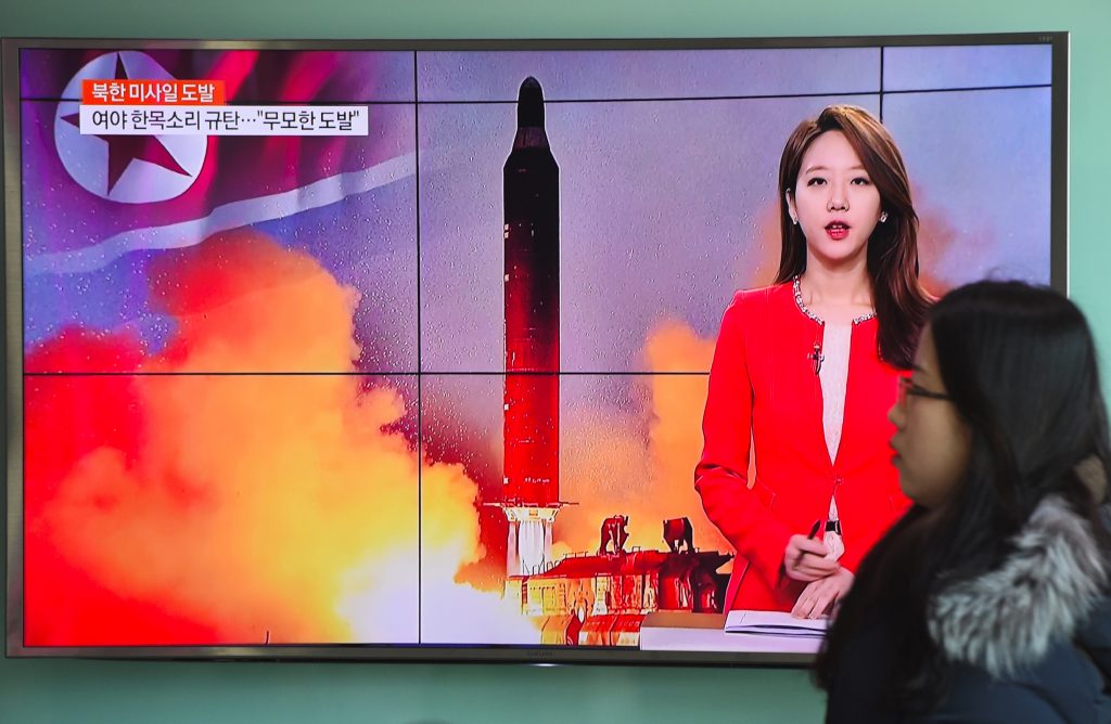 Une passante devant un écran de télévision montrant les images du tir "réussi" d'un missile à portée intermédiaire par la Corée du Nord, à Séoul le 12 février 2017. (Crédits : JUNG Yeon-Je / AFP)