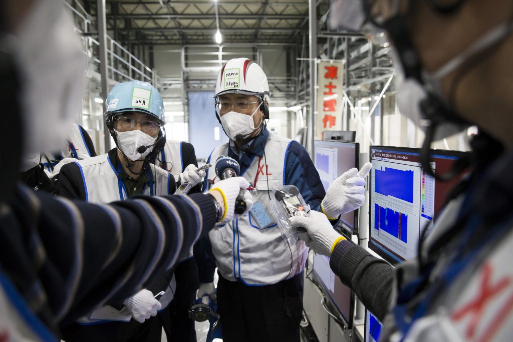 Un employé de la TEPCO (Tokyo Electric Power Co) répond aux questions des journalistes devant l'écran de contrôle d'un bâtiment réfrigéré du groupe nippon à la centrale nucléaire de Fukushima Dai-ichi à Okuma, le 23 février 2017. (Crédits : AFP PHOTO / POOL / Tomohiro Ohsumi)