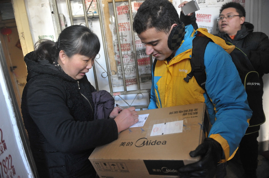 Un étudiant étranger employé par l'entreprise chinoise d'e-commerce Sunning livre un courrier à une cliente chinoise pour le Nouvel an lunaire à Nankin le 30 janvier 2016.