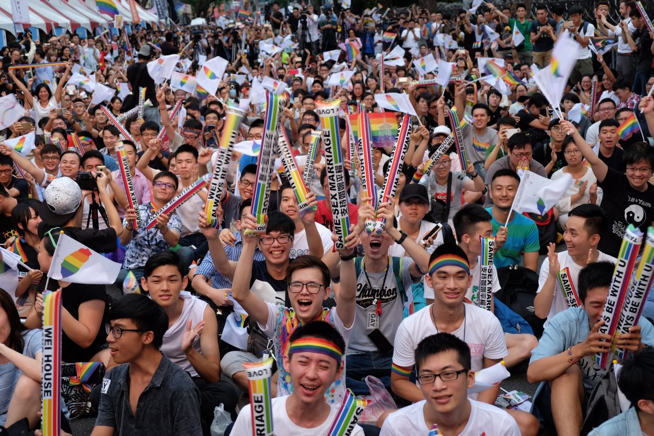 Devant le Parlement, des manifestants célèbrent la décision historique de la Cour constitutionnelle taïwanaise ouvrant la voie à la légalisation du mariage pour les couples homosexuels, le 24 mai 2016. (Crédit : SAM YEH / AFP)