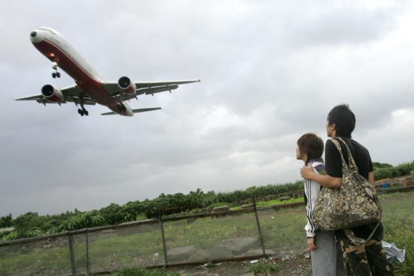 Un jeune couple regarde un avion atterrir à l'aéroport de Taipeï le 12 juillet 2006.