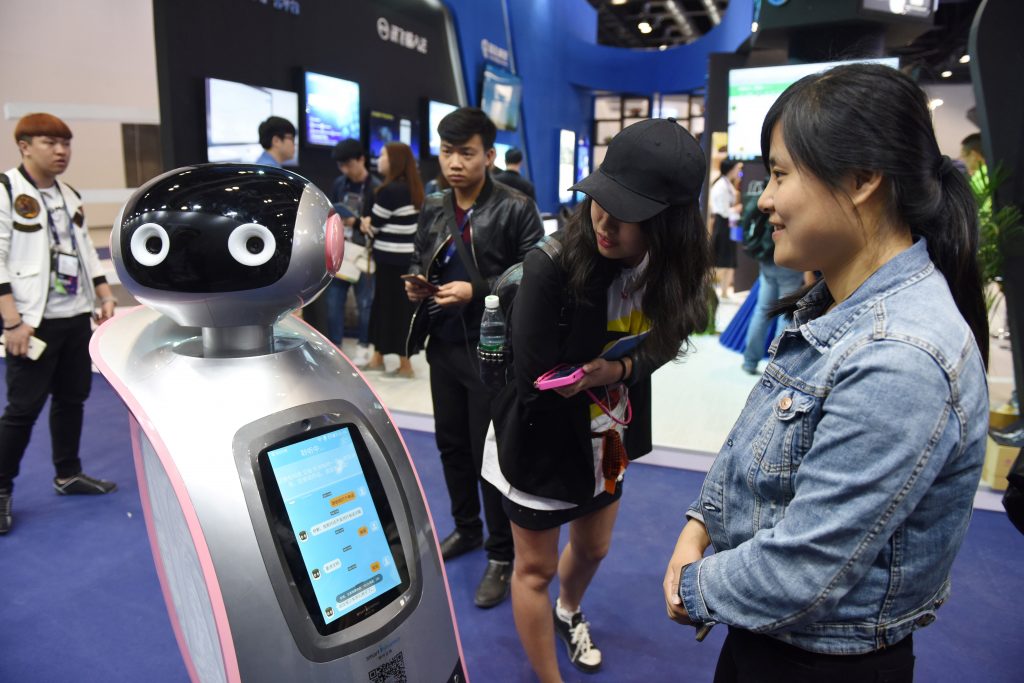 Des visiteurs chinois interagissent avec un robot lors de la Global Mobile Internet Conference (GMIC) à Pékin le 27 avril 2017. (Crédits : AFP PHOTO / Greg Baker)