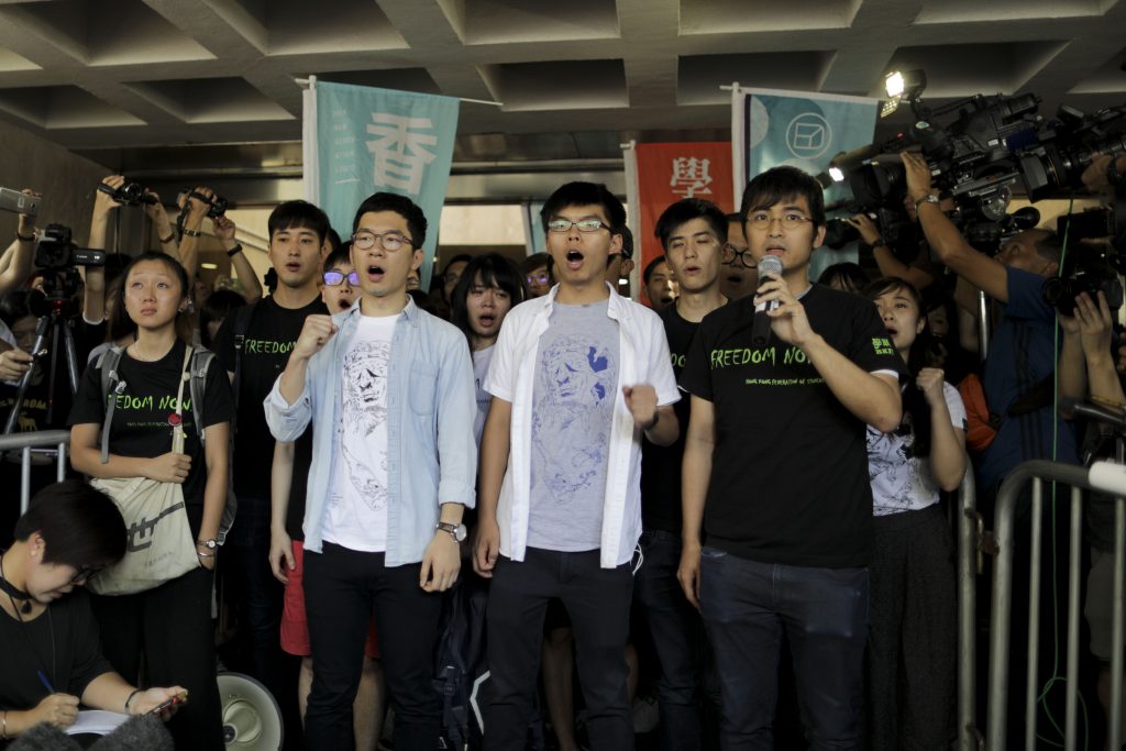Les trois leaders du mouvement des parapluies, (de gauche à droite) Nathan Law, Joshua Wong et Alex Chow, chantent des slogans avant leur condamnation à de la prison ferme le 17 août 2017 à Hong Kong. (Crédits : EyePress News / EyePress / via AFP)