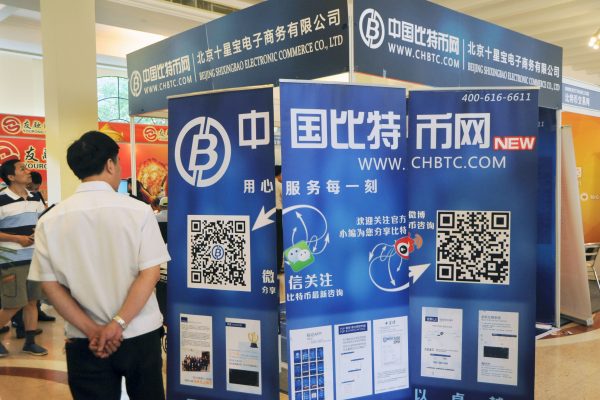 Un visiteur chinois s'arrête au stand de Chbtc.com, l'une des plateformes chinoises d'échange de bitcoins lors d'une salon à Shanghai, en Chine, le 28 juin 2014. (Crédits : Zhu lan / Imaginechina / via AFP)