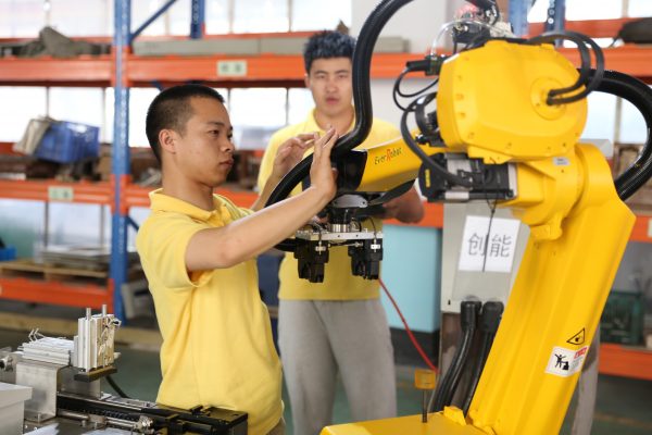 -Un ouvrier chinois teste un bras robotique dans l'usine de Zhejiang EverRobot Robotics à Jiaxing, dans la province côtière du Zhejiang, au sud de Shanghai, le 25 août 2015. (Crédits : Wei wei / Imaginechina / via AFP)