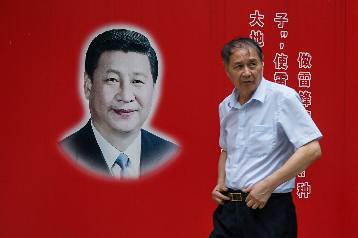 Un habitant de Shanghai passe devant une photo du président chinois Xi Jinping le 28 septembre 2017. (Crédits : AFP PHOTO / CHANDAN KHANNA)
