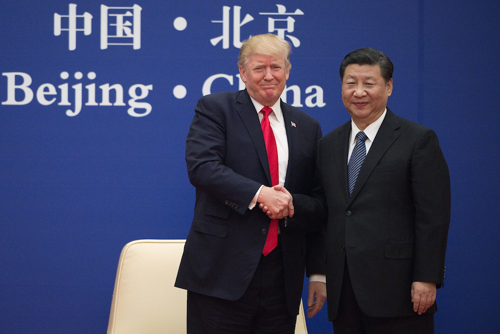 Le président américain Donald Trump se force à sourire en serrant la main de son homologue chinois Xi Jinping lors de la signature de gros contrats au Grand Hall du Peuple à Pékin le 9 novembre 2017. (Crédits : AFP PHOTO / Nicolas ASFOURI)
