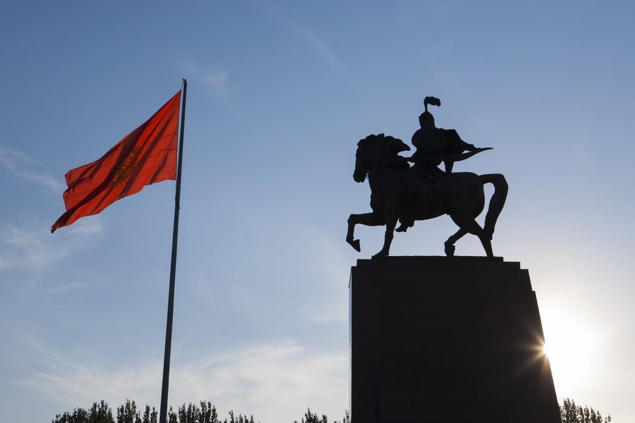 Le drapeau du Kirghizistan flotte devant la statue de Manas, place Ala-Too, à Bichkek. (Crédit : ESCUDERO PATRICK / HEMIS.FR / HEMIS, via AFP)