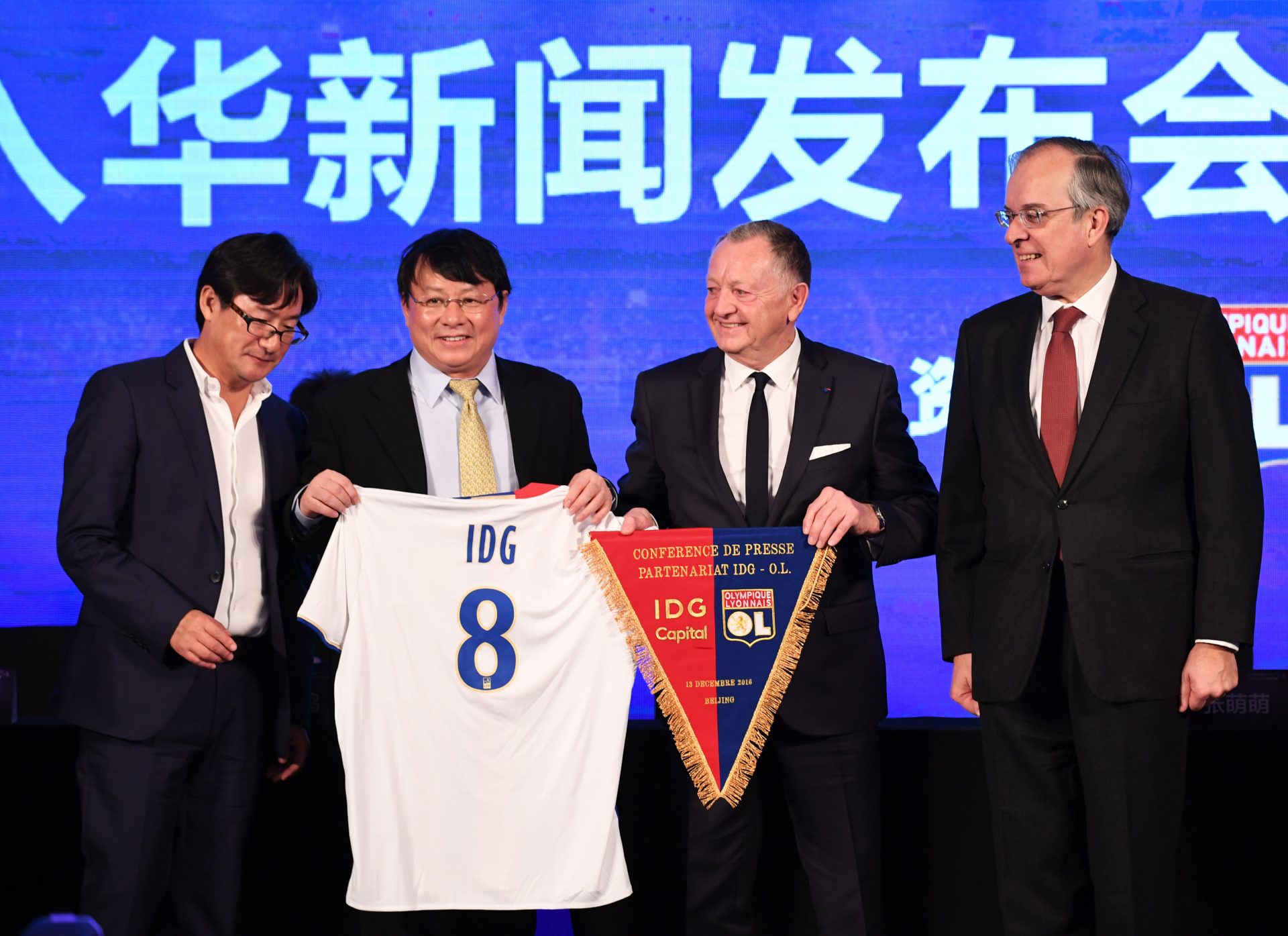C'était il y a un plus d'un an : le président de l'Olympique Lyonnais Jean-Michel Aulas (deuxième à droite) et à ses côtés, le fondateur d'IDG Capital Partners Xiong Xiaoge lors de la cérémonie marquant l'entrée du fonds d'investissement chinois dans le capital du club de football français à hauteur de 20%, à Pékin le 13 décembre 2016. (Crédits : AFP PHOTO / Greg Baker)