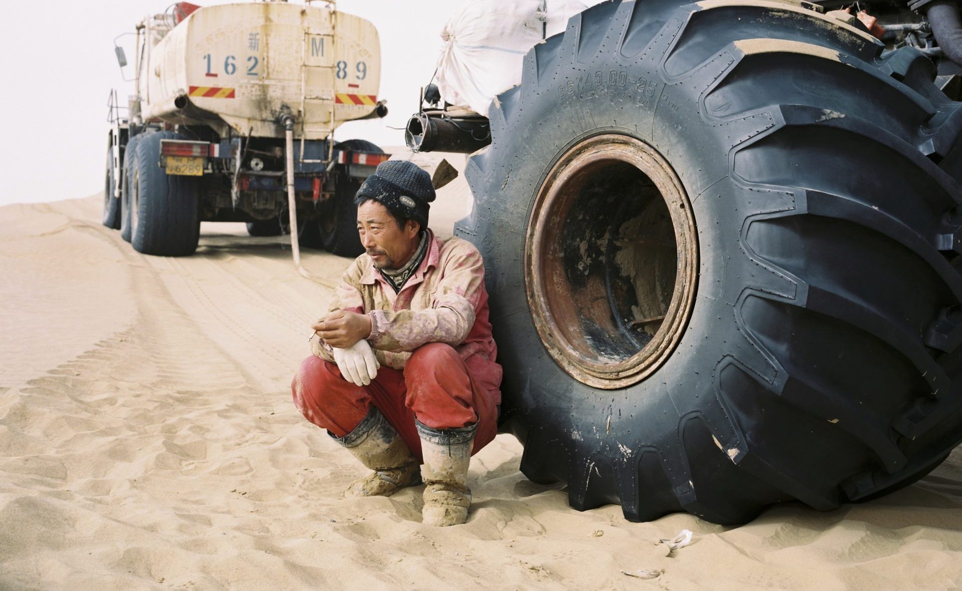 Décembre 2016. Un technicien qualifié de la compagnie pétrolière étatique chinoise CNPC, adossé à son véhicule après le déjeuner, dans le désert du Taklamakan dans la province chinoise du Xinjiang. (Copyright : Patrick Wack)