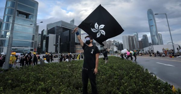Un manifestant agitant le drapeau de Hong Kong sur fond noir. (Source : CNN)