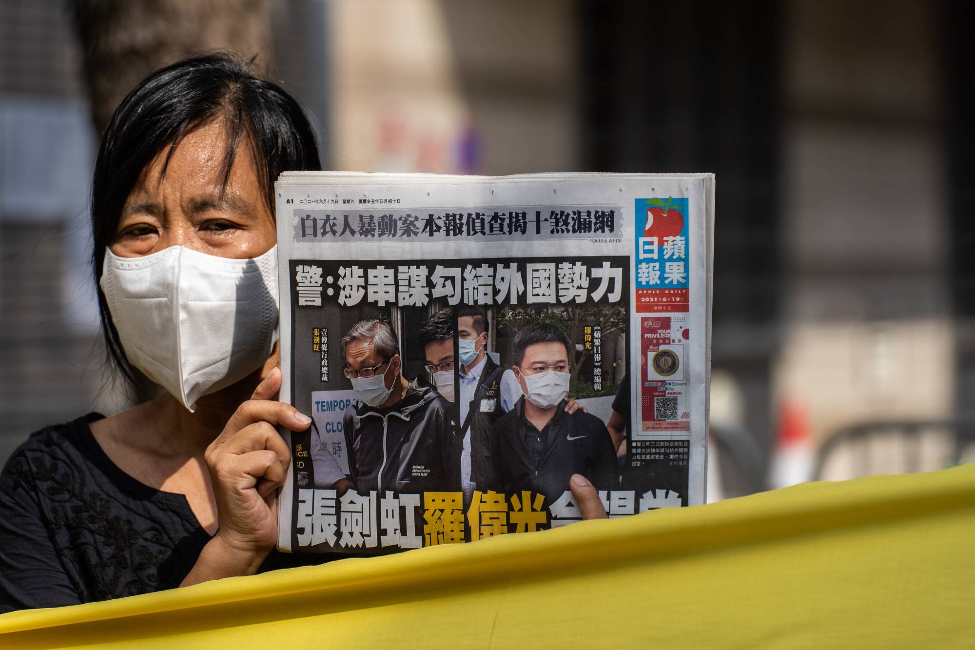 Une Hongkongaise tient la Une du quotidien "Apple Daily" avant la comparution de son directeur général Cheung Kim-hung et de son rédacteur en chef Ryan Law devant le Tribunal de West Kowloon à Hong Kong, le 19 juin 2021. (Source : Japan Times)