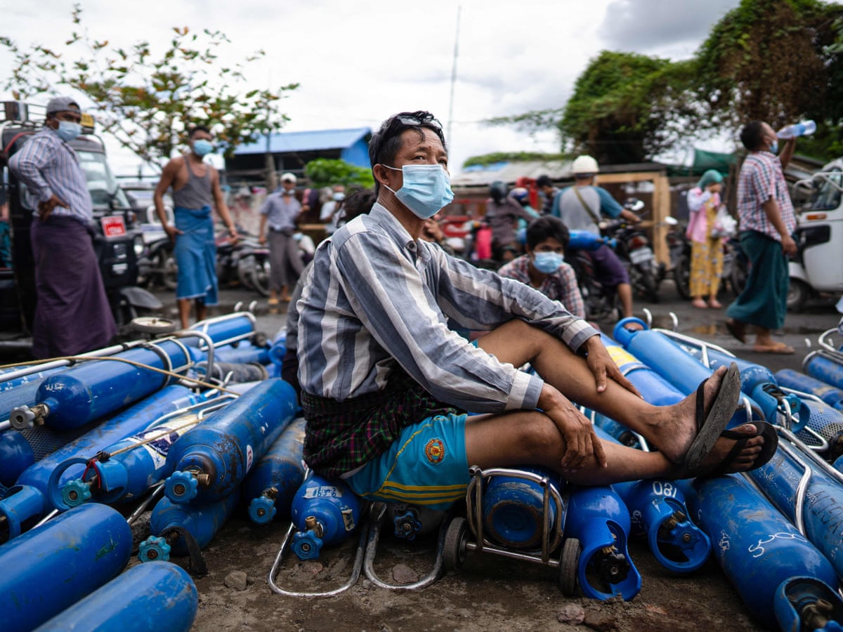 Un homme assis sur des bonbonnes d'oxygène vides dans l'attente de les remplir devant une usine à Mandalay, le 13 juillet 2021. (Source : Wowkeren)