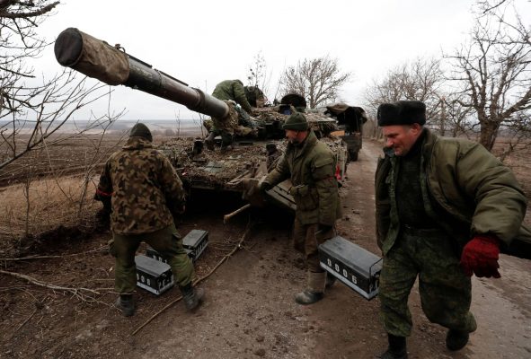 Des séparatistes ukrainiens pro-russes près d'un tank abandonné sur la route entre les deux localités séparatistes de Mykolaivka et Buhas, en pleine dinvasion de l'Ukraine, dans la région de Donetsk, le 1er mars 2022. (Source : Japan Times)