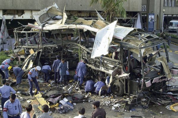 Des agents de sécurité pakistanais examinent la carcasse du bus détruit par un attentat-suicide alors qu'il transportait notamment une douzaine de Français, devant l'hôtel Sheraton à Karachi le 8 mai 2022. (Source : Humanite)