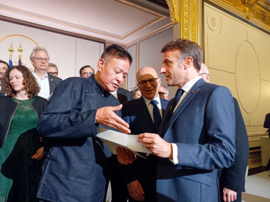 Le Sikyong Penpa Tsering, chef du gouvernement tibétain en exil, offre au président français Emmanuel Macron une photo du Dalai-lama et du locataire de l'Élysée, le 30 avril 2024, à Paris. (Source : RFA)