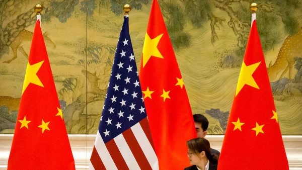 Des membres du personnel chinois ajustent les drapeaux des Etats-Unis et de la Chine.